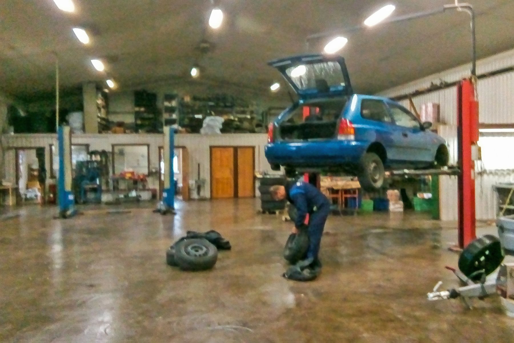 Car raised on a two-post lift inside a general automotive repair workshop